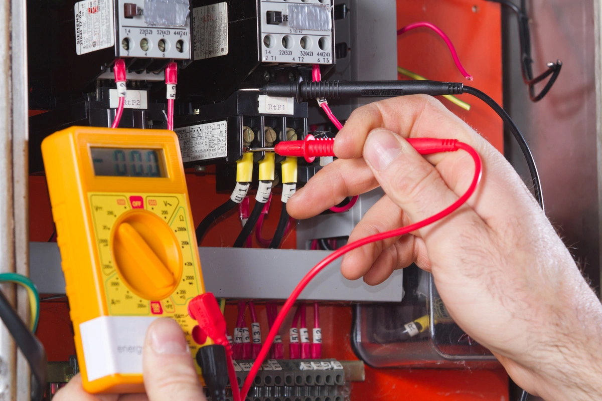 Technicien en train de tester un tableau électrique pour diagnostiquer un problème lors d'un dépannage.