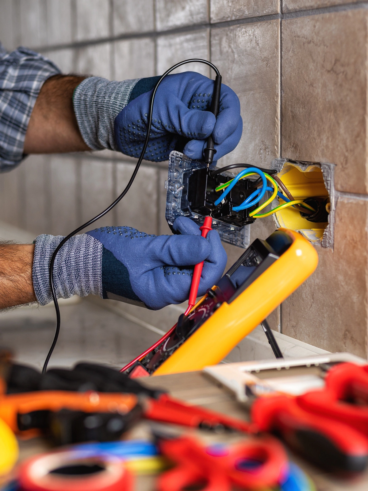 Un électricien effectuant une mesure de tension sur une prise murale pour assurer la conformité des installations électriques.