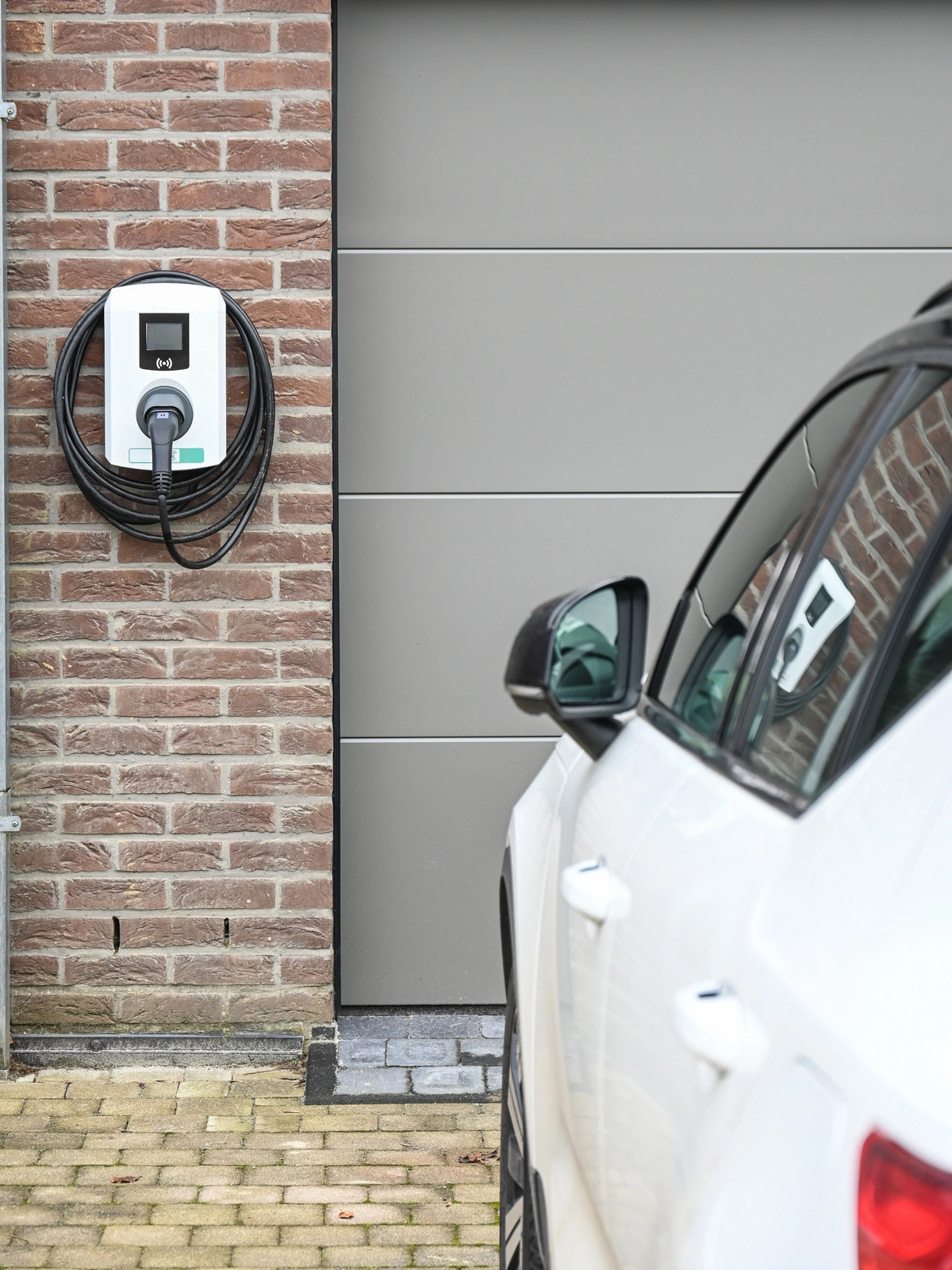 Borne de recharge électrique installée sur un mur de garage, prête à être utilisée pour recharger un véhicule.