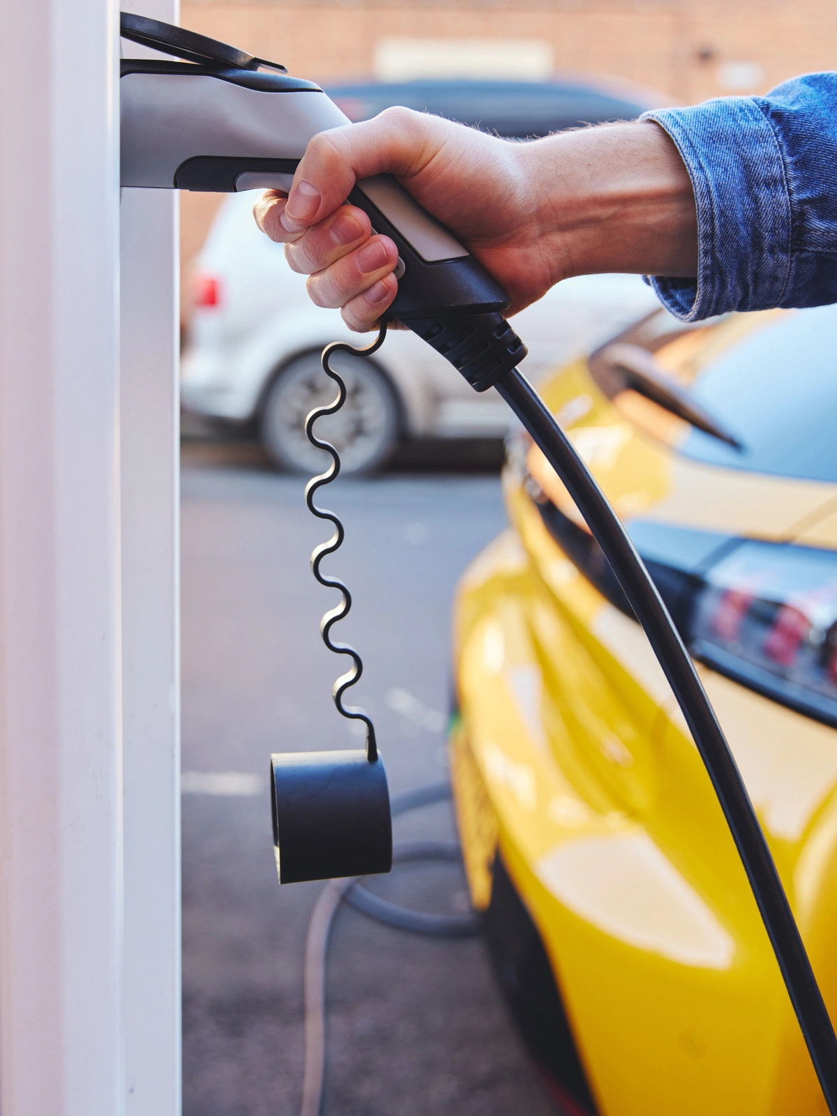 Main tenant une prise de recharge pour véhicule électrique, illustrant le processus d'installation de bornes de recharge.